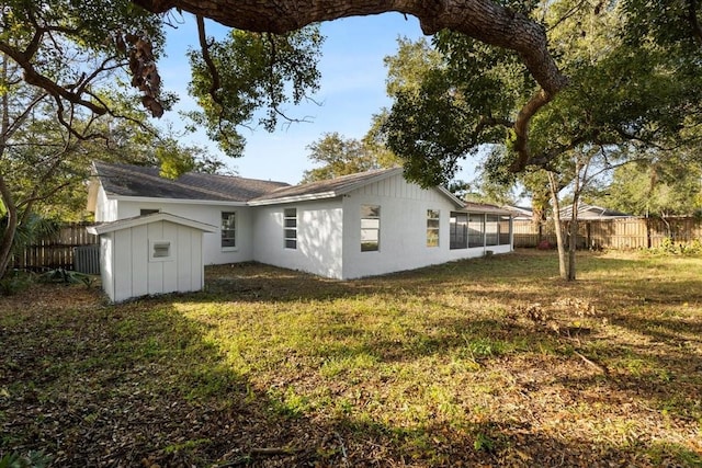 rear view of property with a sunroom, a shed, and a lawn