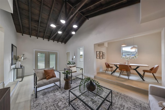 living room with wooden ceiling, high vaulted ceiling, french doors, beam ceiling, and light hardwood / wood-style floors