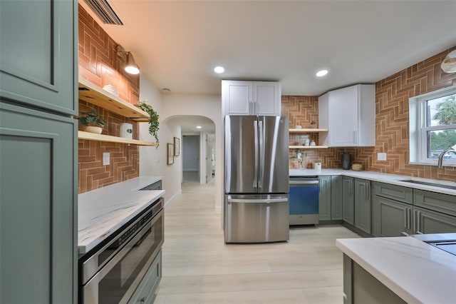 kitchen featuring decorative backsplash, stainless steel appliances, white cabinets, and sink