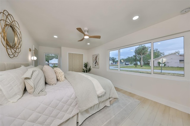 bedroom featuring ceiling fan, light hardwood / wood-style floors, a closet, and multiple windows