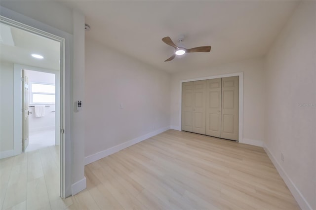 unfurnished bedroom featuring ceiling fan, a closet, and light wood-type flooring