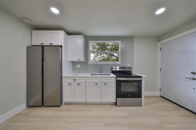 kitchen with white cabinets, sink, light hardwood / wood-style flooring, appliances with stainless steel finishes, and tasteful backsplash