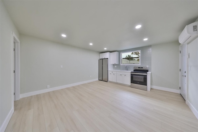 kitchen with sink, appliances with stainless steel finishes, light hardwood / wood-style floors, white cabinetry, and a wall unit AC