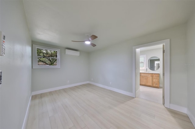 spare room featuring a wall mounted air conditioner, ceiling fan, light hardwood / wood-style floors, and sink