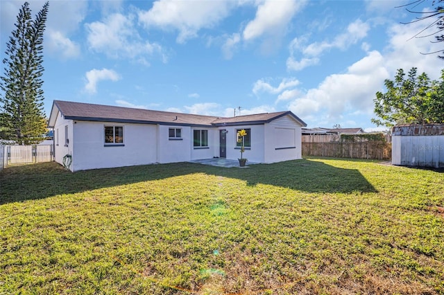 back of property with an outbuilding, a yard, a fenced backyard, and stucco siding