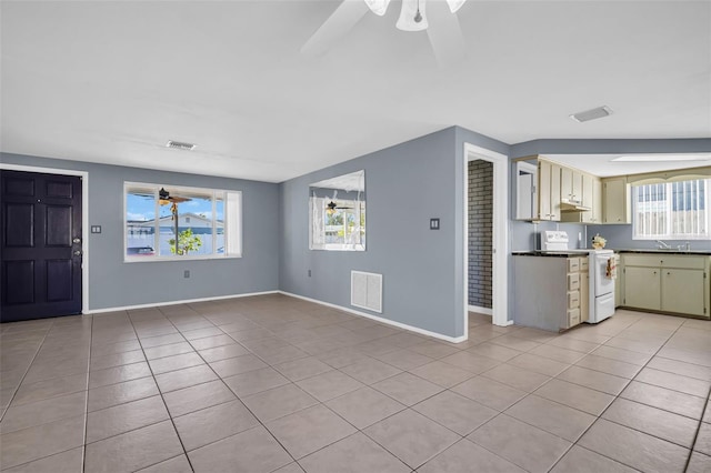 unfurnished living room featuring ceiling fan, light tile patterned floors, and a healthy amount of sunlight