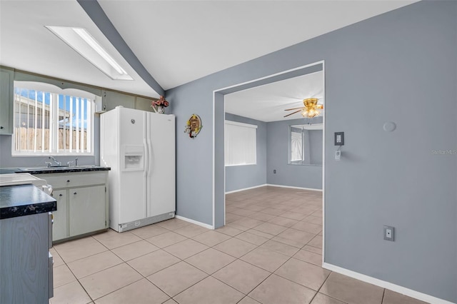 kitchen with white fridge with ice dispenser, a wealth of natural light, vaulted ceiling, ceiling fan, and light tile patterned floors