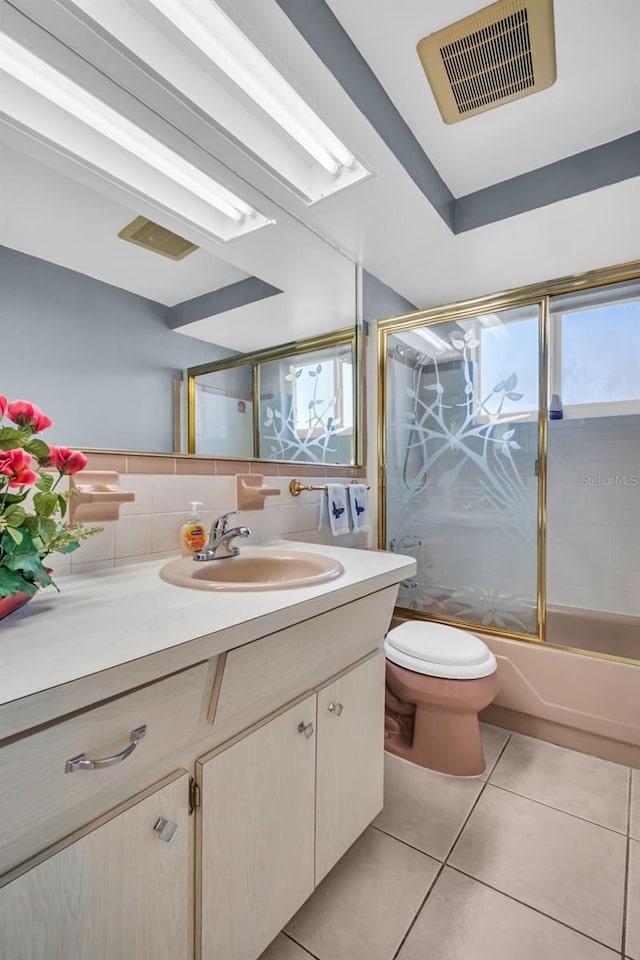 full bathroom with tile patterned floors, vanity, bath / shower combo with glass door, backsplash, and toilet