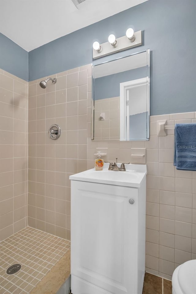 bathroom with vanity, tile walls, tile patterned floors, and a tile shower