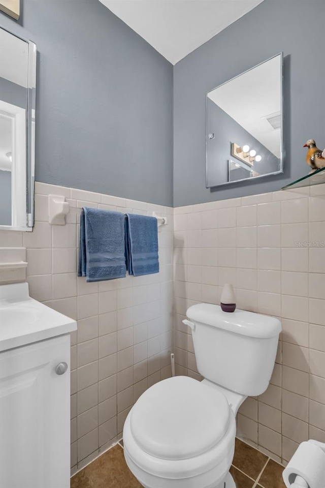 bathroom featuring toilet, vanity, tile walls, and tile patterned floors