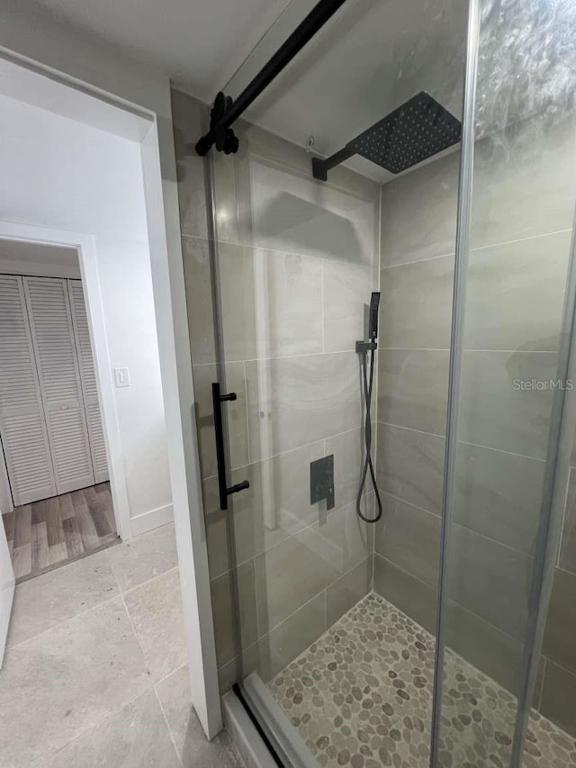 bathroom with wood-type flooring and an enclosed shower