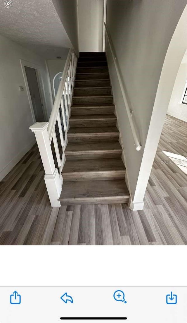 staircase featuring a textured ceiling and hardwood / wood-style flooring