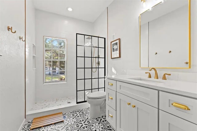 bathroom with vanity, toilet, and a tile shower