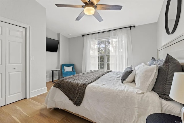 bedroom featuring a closet, light hardwood / wood-style floors, vaulted ceiling, and ceiling fan