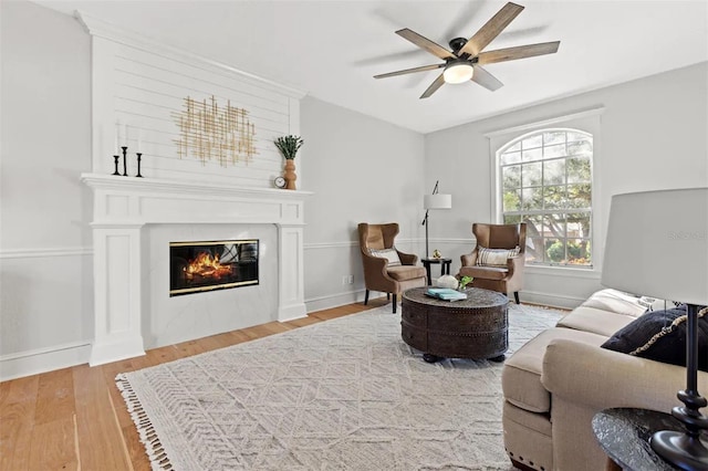 living room with ceiling fan, wood-type flooring, and a fireplace