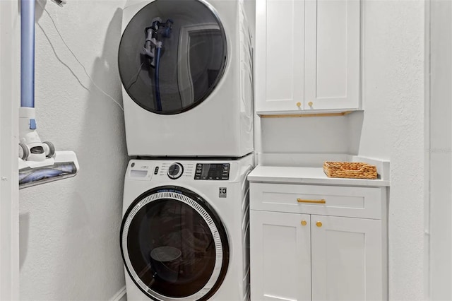 laundry area with cabinets and stacked washer and clothes dryer