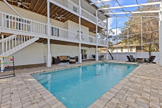 view of pool with outdoor lounge area, ceiling fan, a patio area, and glass enclosure