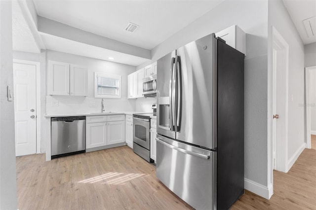 kitchen with white cabinets, stainless steel appliances, light hardwood / wood-style floors, and sink