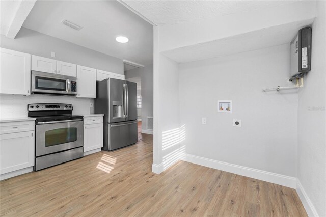 kitchen featuring appliances with stainless steel finishes, a textured ceiling, water heater, white cabinets, and light hardwood / wood-style floors