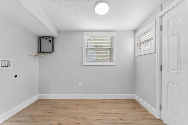 laundry room featuring electric dryer hookup, a textured ceiling, hookup for a washing machine, and light hardwood / wood-style flooring