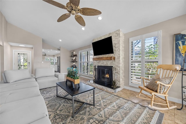 living room featuring vaulted ceiling, plenty of natural light, a stone fireplace, and ceiling fan