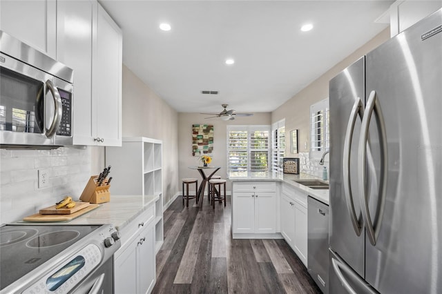 kitchen featuring sink, light stone counters, dark hardwood / wood-style flooring, white cabinets, and appliances with stainless steel finishes