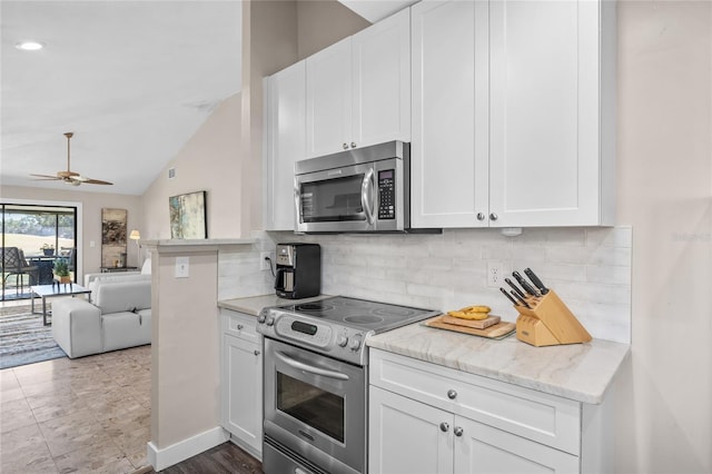 kitchen with appliances with stainless steel finishes, backsplash, white cabinetry, and lofted ceiling