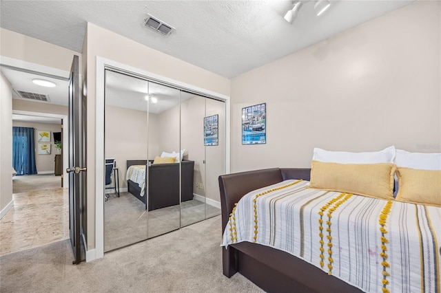 bedroom with a textured ceiling, light colored carpet, and a closet