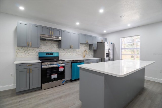 kitchen featuring decorative backsplash, appliances with stainless steel finishes, light wood-type flooring, and a kitchen island