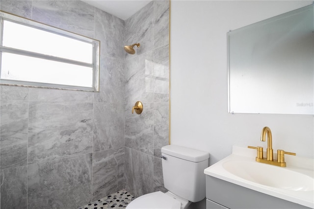 bathroom with vanity, toilet, and tiled shower