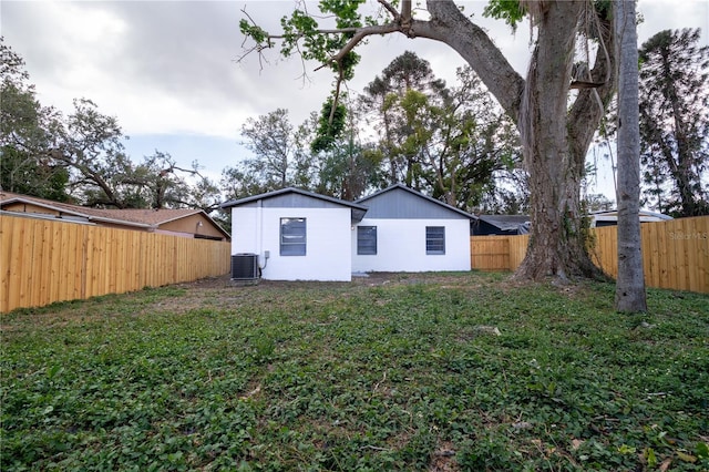 rear view of property with a yard and central AC unit