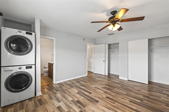 laundry area featuring ceiling fan, stacked washer / drying machine, and dark hardwood / wood-style floors