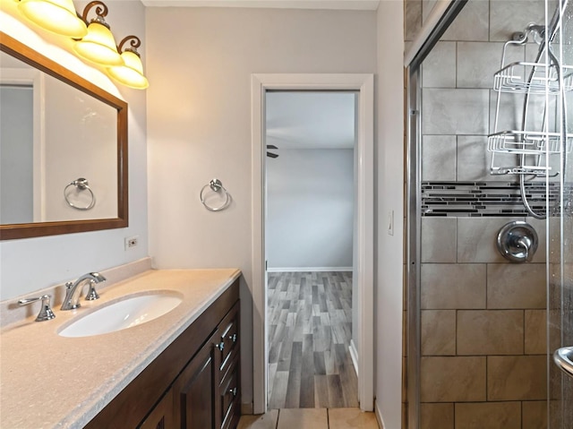 bathroom featuring a shower with shower door and vanity