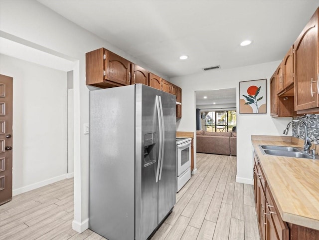 kitchen featuring white electric stove, sink, stainless steel refrigerator with ice dispenser, and light hardwood / wood-style flooring