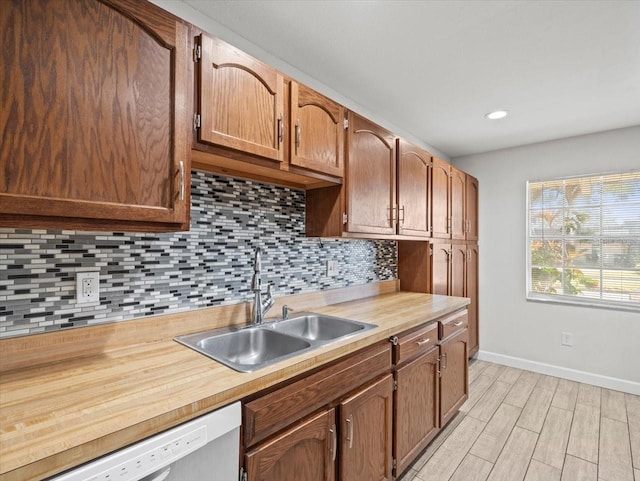 kitchen featuring tasteful backsplash, sink, white dishwasher, and light hardwood / wood-style floors