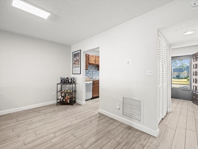 empty room featuring a textured ceiling and light hardwood / wood-style floors