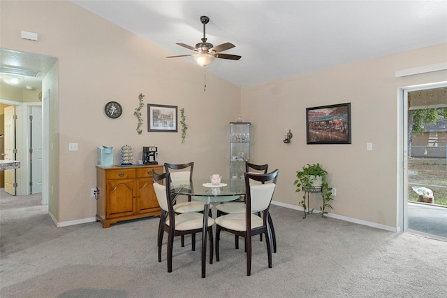 dining space featuring ceiling fan, light colored carpet, and vaulted ceiling