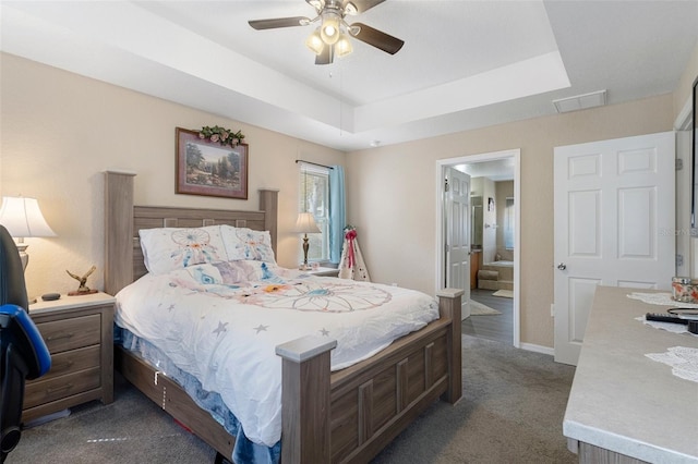 bedroom featuring a raised ceiling, ceiling fan, and dark colored carpet