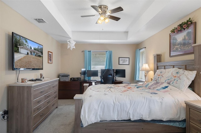 carpeted bedroom featuring ceiling fan and a raised ceiling