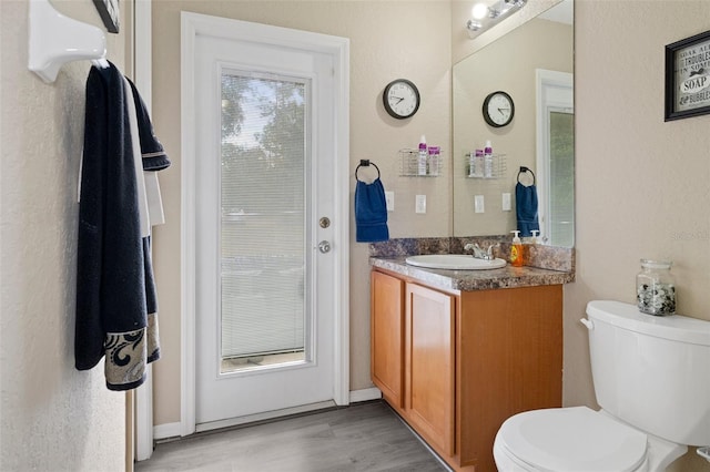 bathroom featuring wood-type flooring, vanity, and toilet