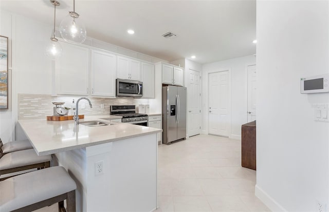 kitchen featuring decorative light fixtures, white cabinetry, a kitchen bar, kitchen peninsula, and stainless steel appliances