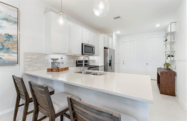 kitchen with white cabinetry, sink, kitchen peninsula, decorative light fixtures, and appliances with stainless steel finishes