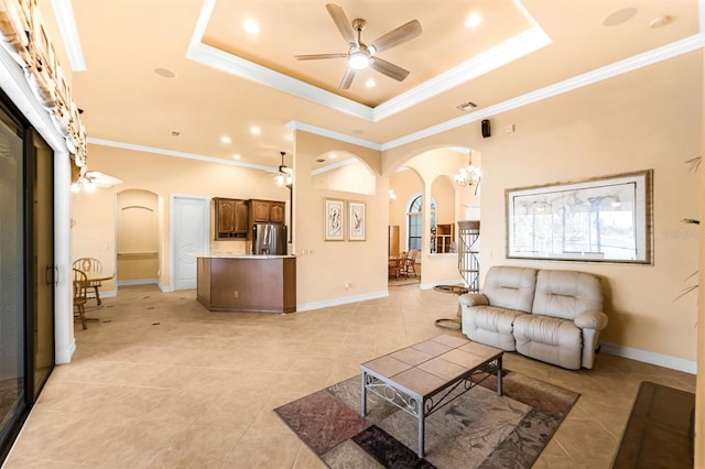 tiled living room with ceiling fan with notable chandelier, a raised ceiling, and ornamental molding