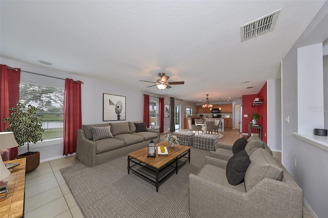 tiled living room featuring ceiling fan with notable chandelier