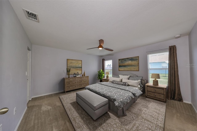 bedroom with ceiling fan, carpet floors, and a textured ceiling