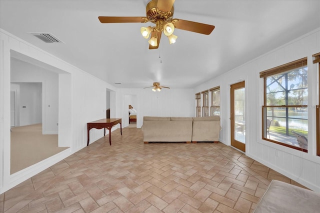 unfurnished living room with ceiling fan and crown molding