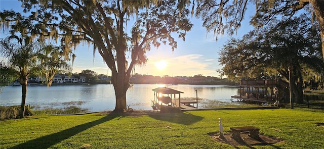 view of dock with a water view and a lawn