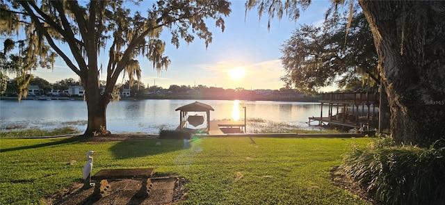 view of dock with a water view and a lawn