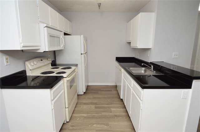 kitchen featuring white appliances, white cabinets, sink, light wood-type flooring, and a textured ceiling