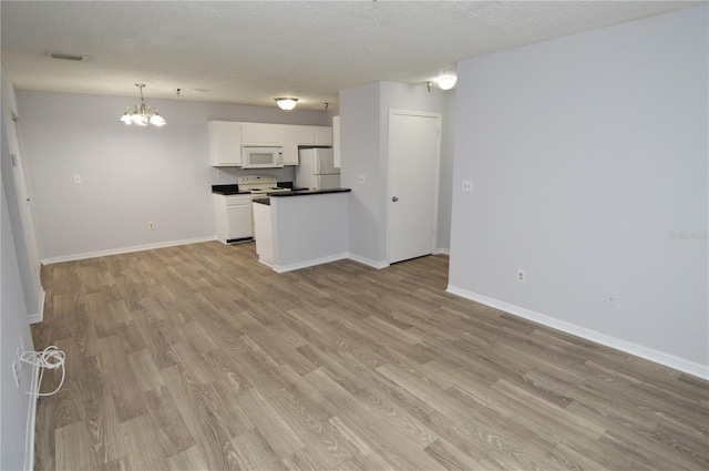 unfurnished living room featuring an inviting chandelier, a textured ceiling, and light hardwood / wood-style flooring